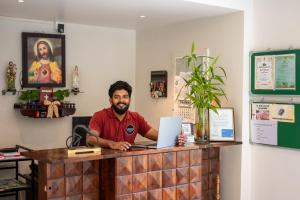 a man sitting at a counter with a laptop at K Mansion in Munnar