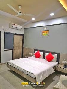1 dormitorio con 1 cama grande con almohadas rojas en HOTEL CM PALACE & GUEST HOUSE & P.G ROOMS, en Kalol