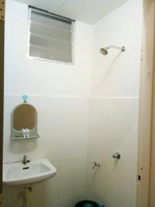 a white bathroom with a sink and a mirror at Homestay Abah Wakaf Che Yeh in Kota Bharu