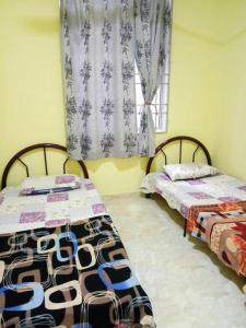 two beds sitting in a room with a window at Homestay Abah Wakaf Che Yeh in Kota Bharu