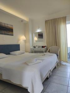 Un dormitorio con una gran cama blanca y una mesa en Filoxenia Beach Hotel en Rethymno Town