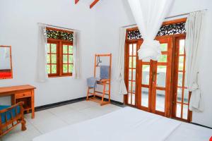 a bedroom with a bed and a desk and windows at Dil's Place in Beruwala +21 photos