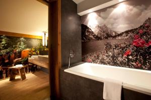 een badkamer met een bad en een schilderij aan de muur bij Sonnenseite Filzmoos in Filzmoos