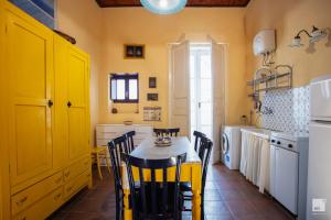 uma cozinha com mesa, cadeiras e armários amarelos em Appartamento La dolce vita em Tropea