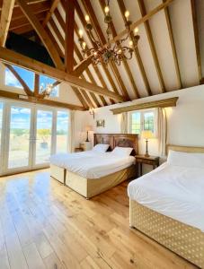 two beds in a room with wooden ceilings and windows at The Mill House on the Brooks South Downs West Sussex Sleeps 15 in Hardham