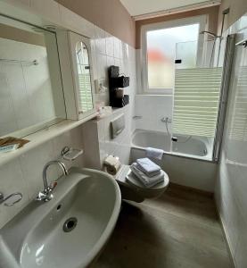 ein Badezimmer mit einem Waschbecken, einem WC und einer Badewanne in der Unterkunft Hotel Vogt in Bad Driburg