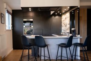 a kitchen with black cabinets and blue bar stools at Appartement 3 pièces à Rennes Chez Guillaume in Vezin-le-Coquet +13 photos