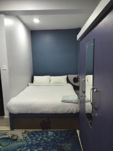 a bedroom with a bed with a blue wall at Hotel Homestay Inn in Thimi