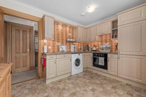 a kitchen with wooden cabinets and a washing machine at The Ploughman's Poet in Bathgate