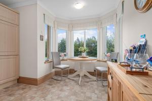 a kitchen with a table and chairs and windows at The Ploughman's Poet in Bathgate