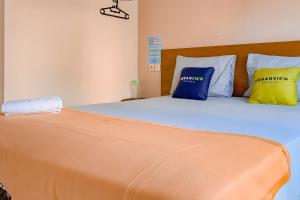 uma cama com almofadas azuis e amarelas em Urbanview Hotel AVA Banjarmasin by RedDoorz em Banjarmasin
