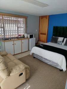 a bedroom with a bed and a couch and a kitchen at 2 on Haig Accommodation, Selbourne, East London in East London