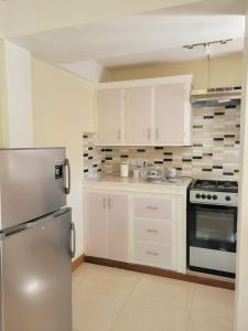 a kitchen with white cabinets and a stainless steel refrigerator at KanXio's Apartment in Pointe Michel