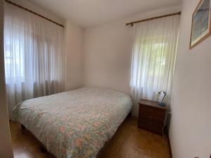 a bedroom with a bed and a window with curtains at Casa Da Rin Emma in Auronzo di Cadore