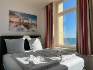 a bed in a bedroom with a large window at Zeitlos Hotel Garni in Scharbeutz