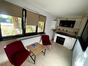 una pequeña cocina con 2 sillas rojas y una mesa en Discret Apartament One, en Târgovişte