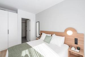 1 dormitorio con cama blanca y cabecero de madera en Be Casa - San Sebastian de los Reyes, en San Sebastián de los Reyes