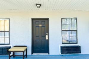 a white building with a black door and a bench at Paradise Inn By OYO Hattiesburg North in Hattiesburg