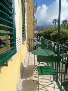 a balcony with green tables and chairs on a building at Casa Gaeta in Gaeta