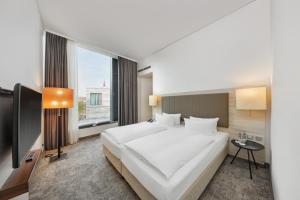 Un dormitorio con una gran cama blanca y una ventana en H4 Hotel Münster, en Münster