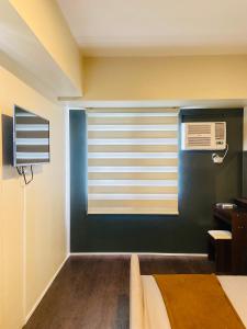 sypialnia z niebieską ścianą i oknem z klimatyzacją w obiekcie Modern Living at Avida Riala w Cebu