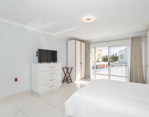 a white bedroom with a bed and a television at Ocean Way Villas - Self Catering in Cape Town