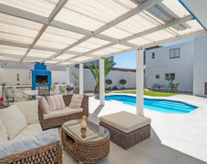 a patio with a white pergola and a pool at Ocean Way Villas - Self Catering in Cape Town