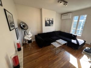 sala de estar con sofá negro y mesa en Beau 3 pièces aux portes de PARIS, en Charenton-le-Pont