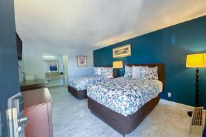 a bedroom with two beds and a blue wall at Paradise Inn By OYO Hattiesburg North in Hattiesburg