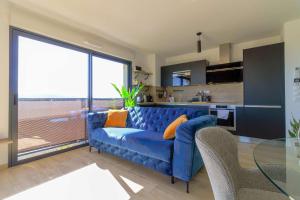 a blue couch in a living room with a kitchen at SELECT'soHOME - Appartement face à la mer avec piscine à Bormes-les-mimosas - CAPNAT-C04 in Bormes-les-Mimosas