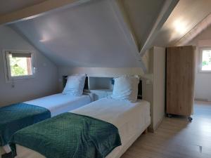 two beds in a small room with two windows at Le Moulin du Porteil in Campagne