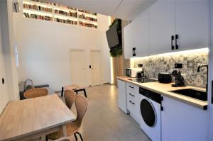 une cuisine avec des armoires blanches et une table avec des chaises dans l'établissement BIBLIOTECA DE LUJO EN EL CENTRO HISTORICO DE MÁLAGa, à Malaga