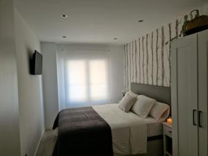 Schlafzimmer mit einem Bett mit weißer Bettwäsche und einem Fenster in der Unterkunft My home in Gijón Apartamento - VUT4494AS in Gijón