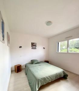 - une chambre avec un lit vert et une fenêtre dans l'établissement Maison de charme, Les Voiles à Sainte Marine, à Combrit