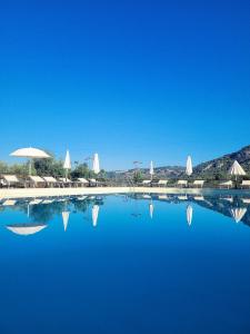 ein Pool mit blauem Wasser, Sonnenschirmen und Stühlen in der Unterkunft Pantalica Ranch Agriturismo Siciliano in Sortino