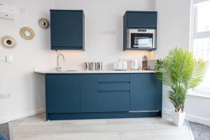 a kitchen with blue cabinets and a sink at Morecambe Bay Studio Flats Free Parking Beach Front in Morecambe