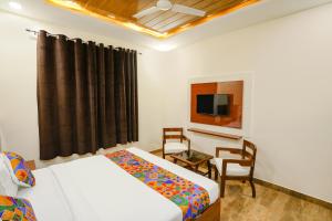 1 dormitorio con 2 camas, escritorio y TV en FabExpress Trijal Inn, en Lucknow