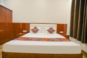 1 dormitorio con 1 cama blanca grande con sábanas coloridas en FabExpress Trijal Inn, en Lucknow
