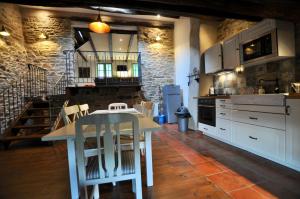 cocina con mesa blanca y armarios blancos en Les Coumayres, en Riols