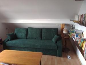 a green couch in a living room with a table at A Kert Apartman in Rezi
