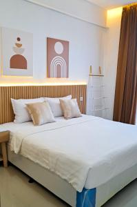 a large bed with white sheets and pillows at Olivia SOHO Guest House in Legian