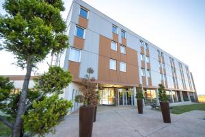 un immeuble de bureaux avec des arbres devant lui dans l'établissement Ibis Styles Dijon Nord Valmy, à Dijon