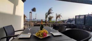 un tavolo con un piatto di frutta e una bottiglia di vino di Promenade Paradise Apartment a San Miguel de Abona