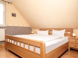 Schlafzimmer mit einem Holzbett mit weißer Bettwäsche in der Unterkunft FH Harmonie in Kaltenhof
