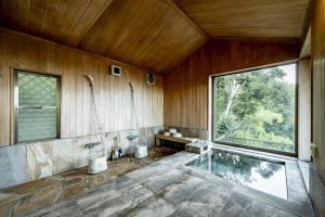 ein Bad mit einer Badewanne, 2 WCs und einem Fenster in der Unterkunft プライベートリゾート碧海 in Okawa