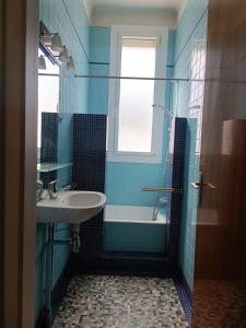 een badkamer met een wastafel, een bad en een raam bij Appartement spacieux in Montreuil