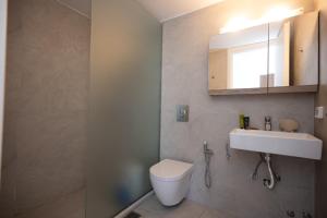 Spilia Apartments & Suites Mykonos في Agrari: حمام مع مرحاض ومغسلة ومرآة