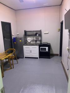 a kitchen with a stove and a microwave in a room at Batman guesthouse in Vientiane