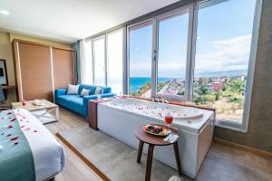 a room with a tub and a bed and a large window at Tilya Resort Hotel in Trabzon