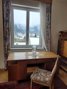 un escritorio frente a una ventana con un jarrón. en Hike Paradise in Carinthia, en Bad Eisenkappel